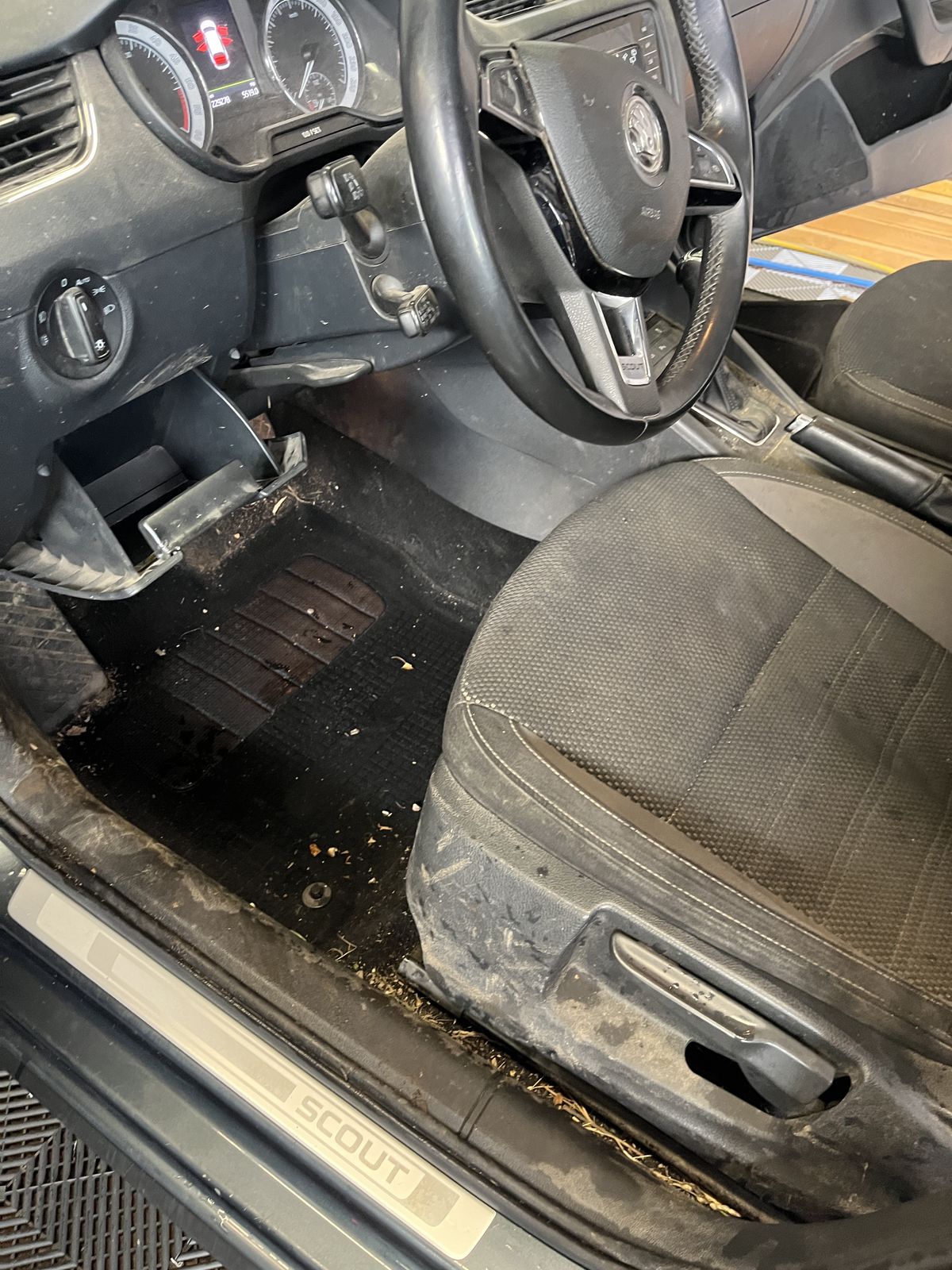Verschmutzter Fahrerfußraum vor der Innenreinigung